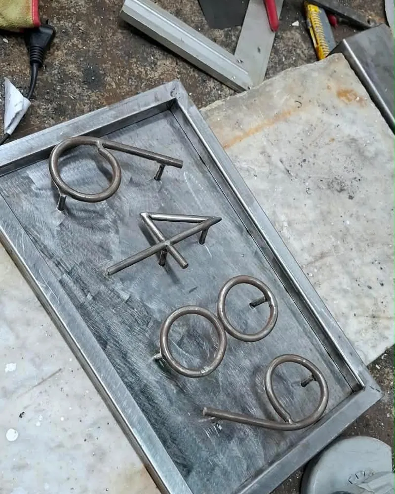 Números de hierro doblados a mano sobre la chapa del cartel, en el taller