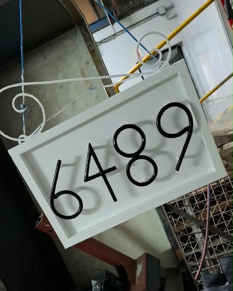 Cartel terminado con el número 6489 en negro sobre fondo blanco, colgado de un soporte