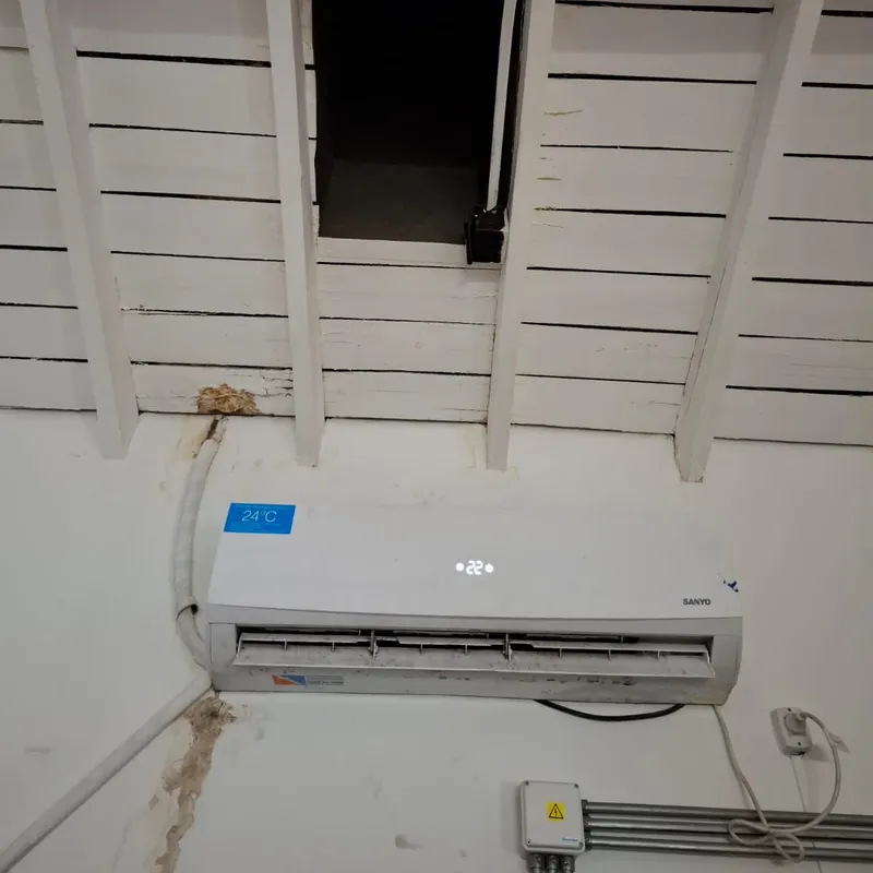 Aire acondicionado split instalado en lo alto de una pared blanca